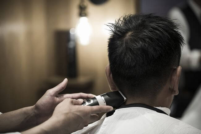フェードカットにするバリカンをもつ理容師の手
